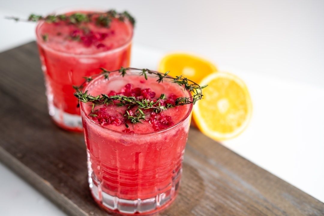 To røde alkoholfrie drinks med timian, bær og appelsin